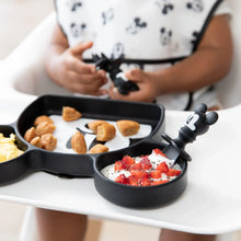 Load image into Gallery viewer, Close-up of a child in a high chair holding Bumkins Silicone Chewtensils®: Mickey Mouse with a matching plate with breakfast foods.
