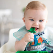 Load image into Gallery viewer, A baby with light hair in a dinosaur bib chews a Bumkins Silicone Chewtensils®: Jade in a high chair.
