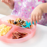 A child enjoys waffles with blueberries using Bumkins Silicone Chewtensils®: Blue Jelly from a pink plate with eggs and bacon.