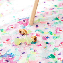 Load image into Gallery viewer, A Bumkins Silicone Chewtensils®: Green Jelly lays on top of a floral mat next to pancake pieces under a high chair leg.
