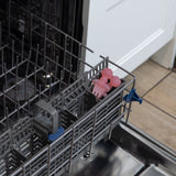 Bumkins Silicone Chewtensils®: Pink Jelly  sit in the utensil compartment of an open dishwasher.