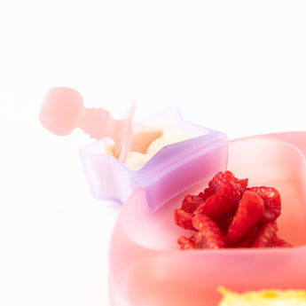 Close-up of Bumkins Silicone Chewtensils®: Pink Jelly in a purple star-shaped cup attached to a pink plate with berries on a white background.