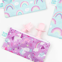 Load image into Gallery viewer, Bumkins Silicone Chewtensils®: Pink peek out of a purple unicorn-print pouch, with two rainbow-print pouches nearby on a white background.
