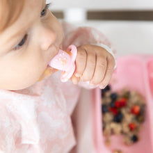 Load image into Gallery viewer, Close-up of a baby in a pink bib with a Bumkins Silicone Chewtensils®: Pink, enjoying baby-led weaning with oats &amp; berries on a pink plate.
