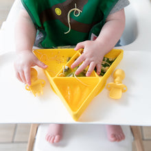 Load image into Gallery viewer, A baby eats from a yellow triangle plate with Bumkins Silicone Chewtensils®: Pineapple nearby on the high chair tray.
