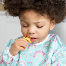 Load image into Gallery viewer, A toddler in a rainbow-patterned bib chews on a Bumkins Silicone Chewtensils®: Pineapple.
