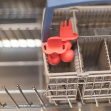 Load image into Gallery viewer, Bumkins Silicone Chewtensils®: Red sits in the utensil compartment of an open dishwasher.
