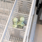 Bumkins Silicone Chewtensils®: Sage sits in the utensil compartment of an open dishwasher.