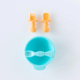 Bumkins Silicone Chewtensils®: Tangerine sit above a blue bowl and spoon set on a white background.