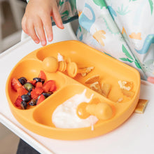 Load image into Gallery viewer, Close-up of a child in a high chair reaching for Bumkins Silicone Chewtensils®: Tangerine on an orange plate with yogurt and berries.
