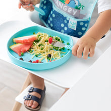 Load image into Gallery viewer, Close-up of a child in a high chair in a blue bib eating pasta, melon, &amp; peas from a blue plate with Bumkins Spoon + Fork: Blue.

