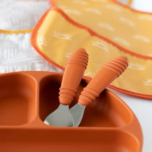 Load image into Gallery viewer, Close-up of Bumkins Spoon + Fork: Clay  in a matching divided plate, with two bibs in the background.
