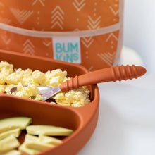 Load image into Gallery viewer, Close-up of a divided orange plate with eggs, avocado, and a Bumkins Spoon + Fork: Clay, with a blurred orange bib in the background.
