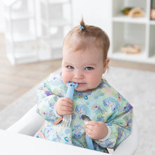 Load image into Gallery viewer, A baby with a topknot smiles in a high chair, holding Bumkins Spoon + Fork: Stitch in a bright playroom.
