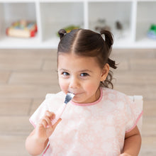 Load image into Gallery viewer, Child wearing a Bumkins Junior Bib: Floral, eating from a Bumkins Spoon + Fork: Pink.
