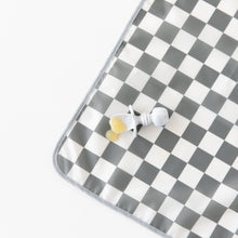 Load image into Gallery viewer, Bumkins Splat Mat: Charcoal Check lays on a white background, with a gray utensil and applesauce on top.

