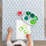 Aerial view of a Bumkins Silicone Grip Dish with Lid (5 Section): Marble with paint & a child with paper on a gray patterned mat.