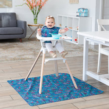 Load image into Gallery viewer, A baby in a highchair smiles wearing a blue bib with a bowl on tray, and a Bumkins Splat Mat: Animal Prints underneath in the bright room.
