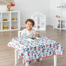 Load image into Gallery viewer, A child paints on Bumkins Splat Mat: Mickey Mouse covering a table in a bright room with toys on shelves.
