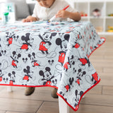 A child paints on paper at a table covered by Bumkins Splat Mat: Mickey Mouse.