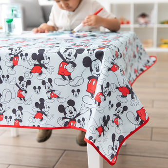 A child paints on paper at a table covered by Bumkins Splat Mat: Mickey Mouse.