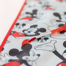 Load image into Gallery viewer, Close-up of a red paintbrush with red paint on top of Bumkins Splat Mat: Mickey Mouse on a white background.
