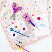 Load image into Gallery viewer, Craft supplies like scissors, paints, and brushes lie on a Bumkins Splat Mat: Princess Magic on a white background.
