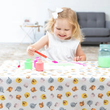 Load image into Gallery viewer, A young girl smiles while painting on a Bumkins Splat Mat: Winnie and Friends, featuring colorful cartoon animal patterns.

