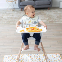 Load image into Gallery viewer, A happy baby in a high chair plays with food on a tray while a Bumkins Splat Mat: Winnie and Friends lays on the floor underneath.
