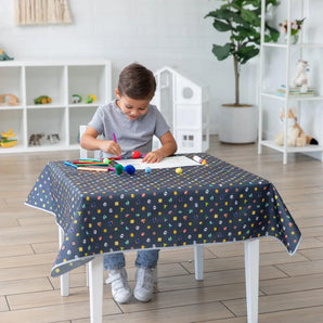 A child draws at a small table covered with a Bumkins Splat Mat: Super Mario™ Lineup  in a bright living room.
