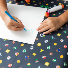 Load image into Gallery viewer, Close-up of a child drawing with a blue marker on paper on a Bumkins Splat Mat: Super Mario™ Lineup.
