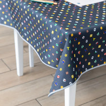Load image into Gallery viewer, Bumkins Splat Mat: Super Mario™ Lineup covers a table on a wood floor, with pencils and paper scattered across the surface.

