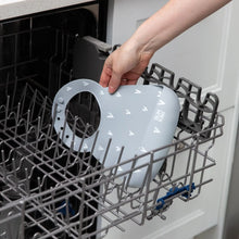 Load image into Gallery viewer, A person places Bumkins Silicone Bib: Hearts in the top rack of an open dishwasher.
