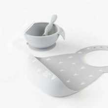 Load image into Gallery viewer, Bumkins Silicone Bib: Hearts rests in front of a gray bowl &amp; spoon set on a white background.
