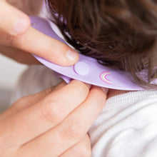 Load image into Gallery viewer, Close-up of hands adjusting the closure of a Bumkins Silicone Bib: Rainbows around a toddler's neck.
