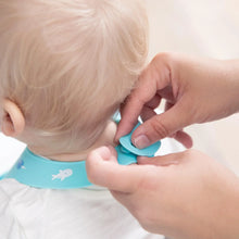 Load image into Gallery viewer, Close-up of hands fastening the closure of a Bumkins Silicone Bib: Ocean Life around a child's neck.

