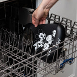 A person places a Bumkins Silicone Bib: Mickey + Minnie Mouse in the top rack of an open dishwasher.