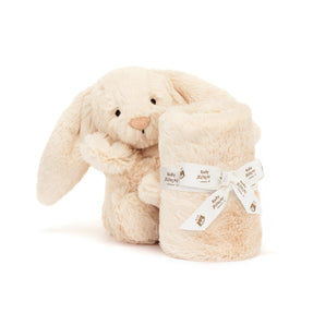 A cream-colored Jellycat Soother Luxe Bunny Willow plush holding a matching baby toy blanket tied with a branded ribbon.