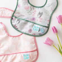 Load image into Gallery viewer, Bumkins Starter Bib 2 Pack: Floral &amp; Lace  rests overlapping on a white background next to three pink tulips.
