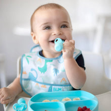 Load image into Gallery viewer, A baby wearing a dinosaur bib in a high chair eats fruit from a blue plate with Bumkins Silicone Chewtensils®: Blue.
