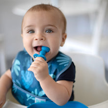 Load image into Gallery viewer, A baby with bright eyes in a blue bib chews a Bumkins Silicone Chewtensils®: Dark Blue.
