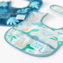 Load image into Gallery viewer, Close-up of Bumkins Starter Bib 2 Pack: Dinosaurs &amp; Blue Tropic laid flat on a white background.
