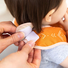 Load image into Gallery viewer, Hands fasten the hook-and-loop closure of an orange Bumkins Starter Bib 2 Pack: Sunshine and Grounded around a child's neck.
