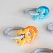 Load image into Gallery viewer, Bumkins Silicone Teething Charms: Orange lays among other teething toys on a white background.
