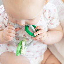 Load image into Gallery viewer, Close-up of a baby in a floral onesie chewing on a Bumkins Silicone Teething Charms: Green.
