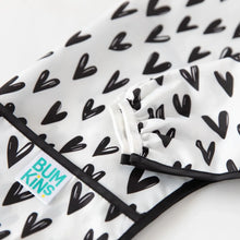 Load image into Gallery viewer, Close-up of Bumkins Sleeved Bib: Hearts on a white background, with focus on the white elastic cuff on the sleeve.
