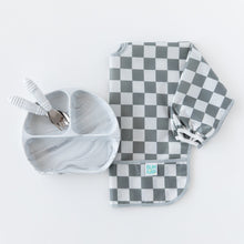Load image into Gallery viewer, Bumkins Sleeved Bib: Charcoal Check is displayed with a gray divided plate and matching utensils on a white background.
