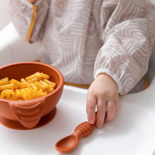 Load image into Gallery viewer, Close-up of a child in a Bumkins Sleeved Bib: Wander reaching for a spoon beside a bowl of mac and cheese on a high chair tray.
