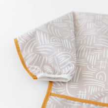 Load image into Gallery viewer, Close-up of Bumkins Sleeved Bib: Wander on a white background, with focus on the white elastic cuff on the sleeve.

