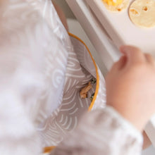 Load image into Gallery viewer, Close-up of a child in a Bumkins Sleeved Bib: Wander with food in the pocket, sitting at a table with tortilla pieces.
